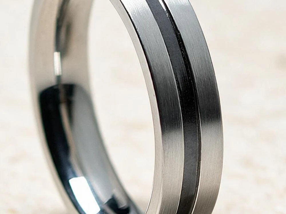 Close-up of the satin finish on a steel wedding band, with the brushed grain visible